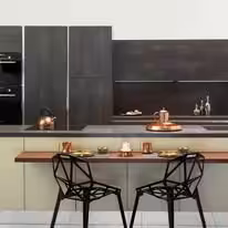 Dark modern kitchen with a walnut dining ledge and wire frame chairs