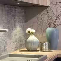 Kitchen backsplash detail in veined stone with ceramic vases on the counter