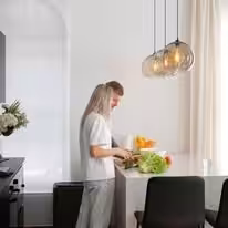 Woman preparing a salad at the counter of a white kitchen