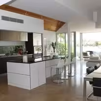 Open plan kitchen with a white island, exposed timber beam and full height glazing