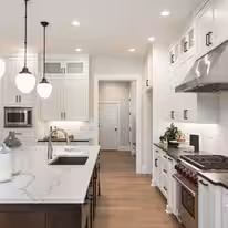 White kitchen with a marble waterfall island and a professional range